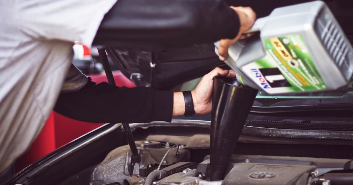 Mechanic pouring fresh engine oil into a car engine during an oil change service